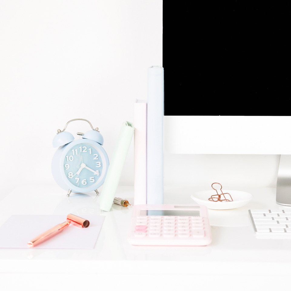 Workspace with stationary and a blue clock to symbolize that it is easy to stop procrastination and get unstuck.